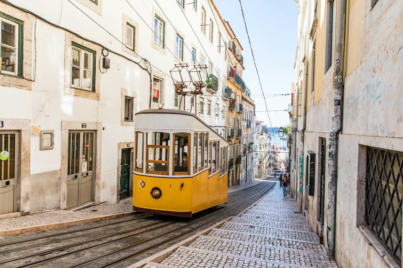 A yellow tram on a cobbled street in Lisbon